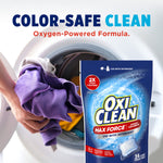 Lifestyle image of hands loading purple clothing into a front-load washer with an OxiClean Max Force pouch and 'Color-Safe Clean' headline
