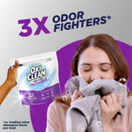 Lifestyle graphic showing a person smelling a towel while another hand holds an OxiClean Triple Action Odor Blasters pouch.