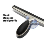 Diagonal product shot of an OXO stainless steel squeegee showing the soft-grip handle and suction hook with copy ‘Sleek stainless steel profile’