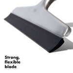 Close-up angled detail of an OXO squeegee blade showing the flexible black rubber edge and stainless steel body