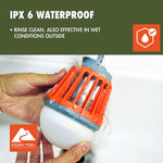 Hands holding an orange Ozark Trail bug zapper lantern under running water to illustrate waterproofing