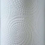 Macro view of embossed circular dot pattern on white paper towel showing texture and quilting detail