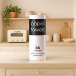 Paper towel roll displayed on a kitchen counter with jars and a toaster in a softly lit home setting