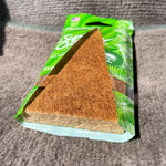 Angled close-up of a brown rectangular air freshener pad inside a green Paradise Air Super Organic Tropic Twist pouch.