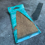 Close-up of Paradise Air Super Organic Tsunami pack with visible triangular felt air freshener on carpeted surface