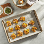 Baked savory bites on parchment-lined sheet pan with small bowls of herbs and dipping sauce nearby