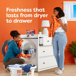 Two people enjoying fresh laundry near a washer with a Bounce Megasheets box on the washer and 'Freshness that lasts' text