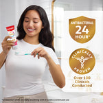 Smiling person applying Colgate Total toothpaste to a toothbrush next to badges for antibacterial 24 hour and clinically proven