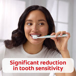 Person brushing teeth with toothbrush, accompanied by text claiming significant reduction in tooth sensitivity