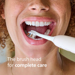 Close-up lifestyle image of a person using a Philips Sonicare electric toothbrush with a brush head visible inside an open mouth.