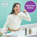 Smiling person brushing teeth at a sink with a tube of Tom's of Maine Whole Care on the counter and a purple callout reading "Removes Stains*."