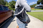 Person carrying a Star brite mesh trash bag over shoulder outdoors, suction-cup clip visible at the top