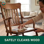 Person wiping a wooden chair seat in a living room with Murphy logo in the corner