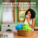 Smiling person inhaling a towel beside a laundry basket and washing machine evoking clean linen scent