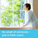 Smiling person leaning toward a bright window with a small vase on the sill and text about fresh scent