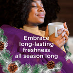 Person wrapped in a purple blanket holding a mug with overlaid text promoting long-lasting freshness and pinecone decorative accents.