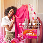 Person smelling a bright pink garment with a Bounce Intense box and floral graphics in foreground