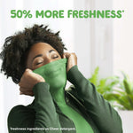 Lifestyle image of a person smelling a green garment with headline text about freshness above on a light background