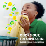 Smiling person inhaling a towel with floating floral graphics and 'odors out, freshness in' tagline