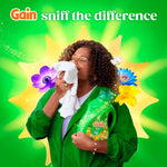 Woman smelling a fabric while holding a Gain Island Fresh bottle with floral illustrations and 'sniff the difference' text