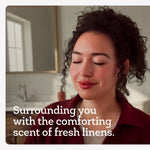 Close portrait of a person with eyes closed in a bathroom interior with overlaid text about comforting linen scent