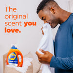 Person smelling a white shirt next to a basket with a Tide Ultra Hygienic Clean bottle and headline about original scent.