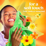 Person smiling while pressing a green towel to their face amid tropical flowers and text about a soft touch