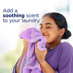 Smiling person holding a purple towel to their face with text encouraging adding a soothing scent to laundry.