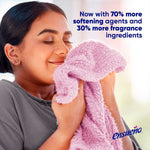 Person smelling a soft pink towel beside text promoting increased softening agents and fragrance ingredients