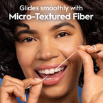 Close portrait of a smiling person flossing with a visible strand of floss and headline about micro-textured fiber