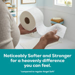 Person holding an embossed Angel Soft Ultra toilet paper roll and unrolling a sheet in a bright bathroom setting.