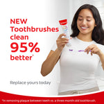 Smiling person holding a tube of Colgate toothpaste and a purple-bristled toothbrush with bold text claiming 'NEW Toothbrushes clean 95% better'.