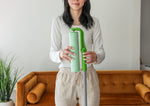 Person holding an Evercare extendable lint roller with a green refill roll in a living room setting