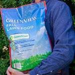 Person holding a close-up bag of GreenView Fall Lawn Food showing the brand name and product graphics
