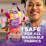 Lifestyle image of a smiling person holding ARM & HAMMER Odor Blasters fabric rinse bottle with text 'safe for all washable fabrics'
