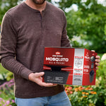 Person holding boxed Ortho Home Defense Mosquito Kill & Prevent product outside in a garden setting