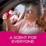 Person inside a car holding a small pink California Scents vent diffuser, smiling and looking at the product