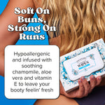 Person holding a Poo-Pourri flushable wipes box with bold benefit text and ingredient callout box on a blue background