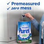 Person holding a Purex Fresh Mountain Breeze pouch while dropping a detergent pac above a countertop with 'Premeasured zero mess' text