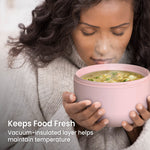Person holding a steaming blush pink insulated bowl of soup close to their face to show warmth and insulation.