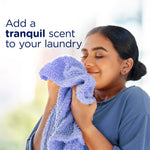 Person holding a soft towel to their face with text 'Add a tranquil scent to your laundry' in the background