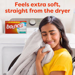 Person hugging a soft blanket near a washer with a small Bounce box graphic and text about extra softness from the dryer
