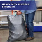 Person lifting a filled gray Hefty Steelsak trash bag in a workshop setting with headline about heavy duty strength