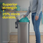 Person lifting a teal Glad bag from a tall stainless kitchen trash can with strength claim text