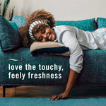 Smiling person reclining on a teal sofa with text overlay reading “love the touchy, feely freshness” in white type.