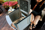 Person lifting the lid of a slate plastic planter showing internal cavity and removable panels on a patio table