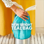 Person placing a bright teal trash bag into a small silver waste bin with text reading "NEW BRIGHT TEAL BAG"