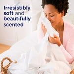 Person smelling a freshly laundered white sheet next to text reading 'Irresistibly soft and beautifully scented'