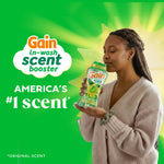 Person holding and smelling a Gain scent booster bottle in a lifestyle ad with 'America's #1 scent' text on green background.