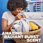 Smiling person smelling laundry from a basket in a laundry room with overlay text promoting Radiant Burst scent